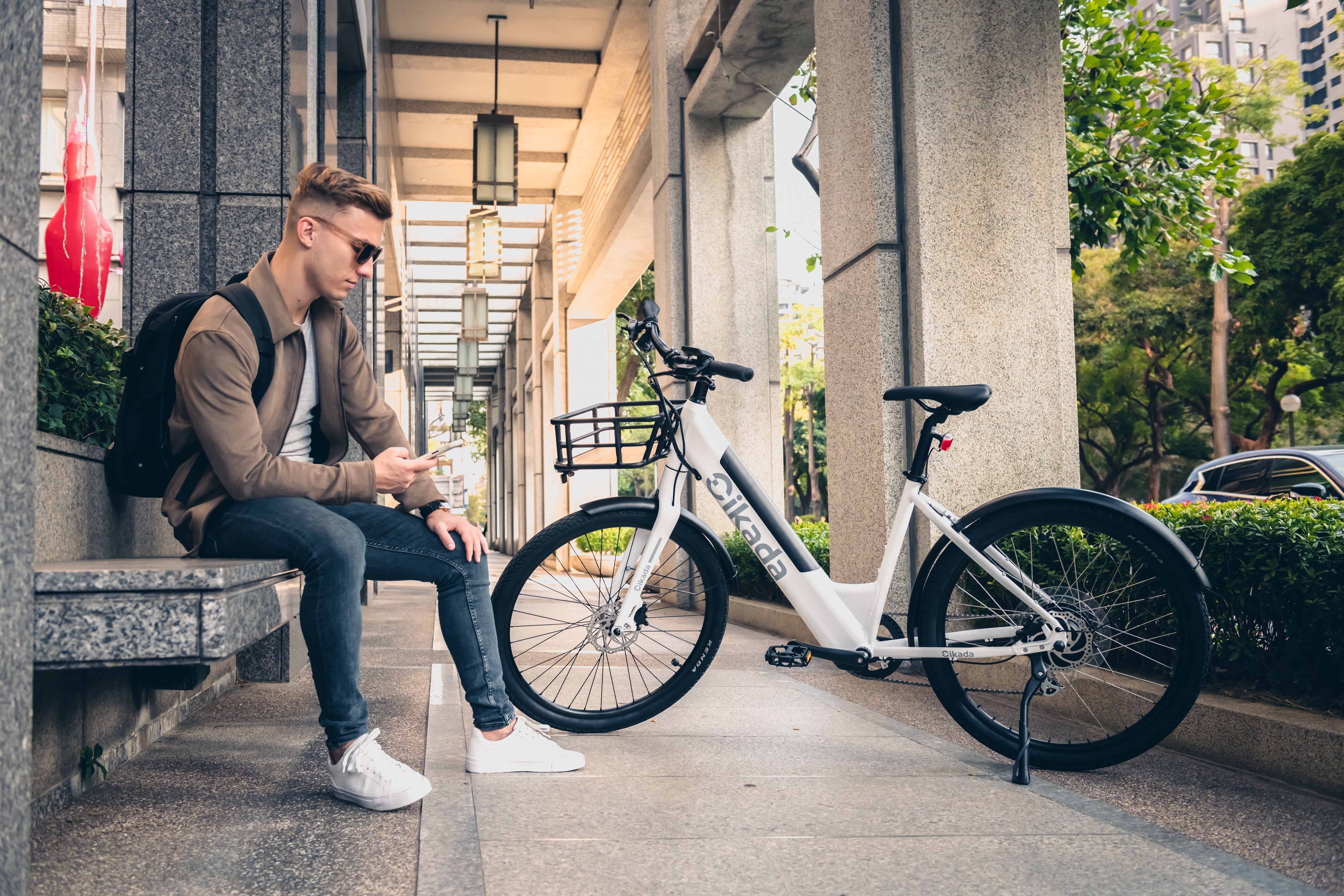 A man is using the Cikada app to connect to his Cikada City e-bike on the side of the road.